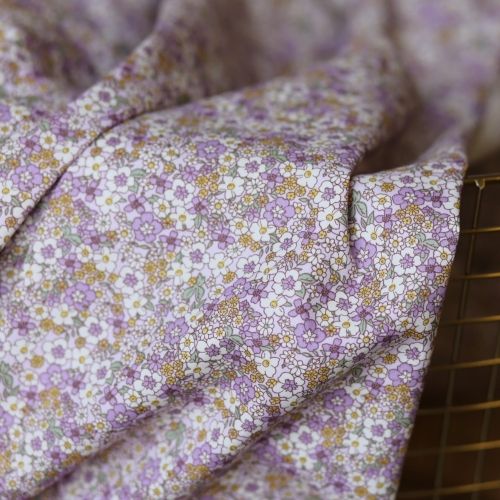 Tkanina bawełniana premium Lila w gęsty wzór drobnych kwiatów w odcieniach fioletu, lawendy i miodu na jasnym tle.
