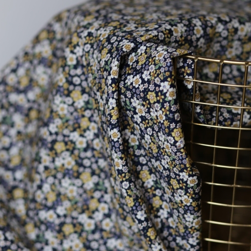 Granatowa tkanina bawełniana premium Lila w gęsty wzór drobnych białych, liliowych i żółtych kwiatów na ciemnym tle.