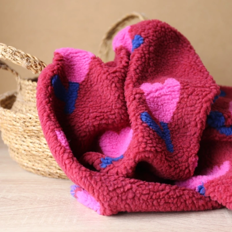 Miękkie futerko sztuczne typu baranek w kolorze malinowej czerwieni, we wzór w różowo-niebieskie kwiaty.