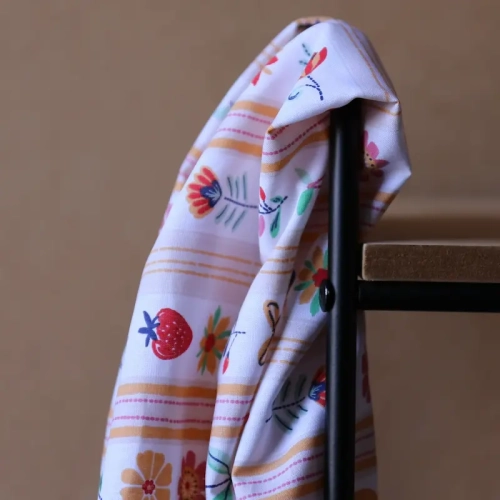 Żółta popelina bawełniana w pionowe pasy, zdobiona radosnym motywem truskawek, cytryn, wisienek oraz kolorowych kwiatów.