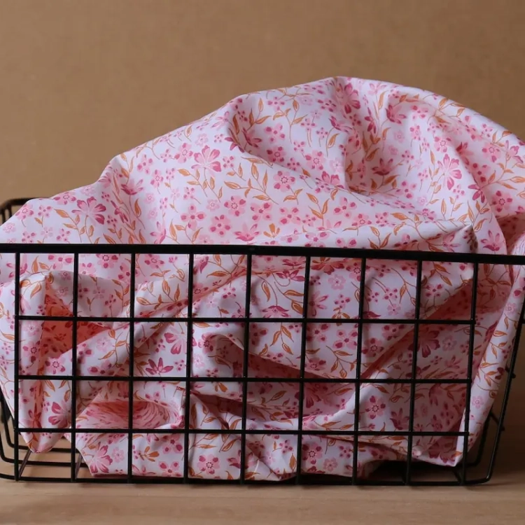 Różowa popelina bawełniana w gęsty wzór drobnych kwiatów i cynamonowych listków o gładkim splocie.