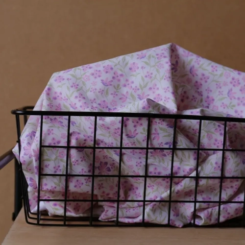 Fioletowa popelina bawełniana Poppy Fabrics w gęsty wzór drobnych lawendowych kwiatów i zielonych listków o gładkim splocie.