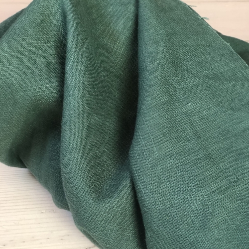 Szlachetna tkanina lniana Fibi w głębokim odcieniu intensywnej zieleni o wyraźnej teksturze i naturalnym splocie.