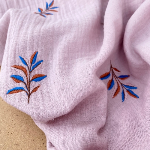 Przybliżenie na haftowane niebiesko-czerwone gałązki na muślinie