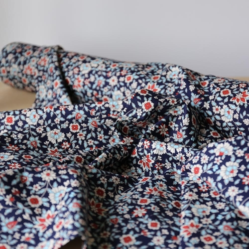 Granatowa tkanina bawełniana premium Lisa w drobny, gęsty wzór biało-błękitnych i czerwonych kwiatów.